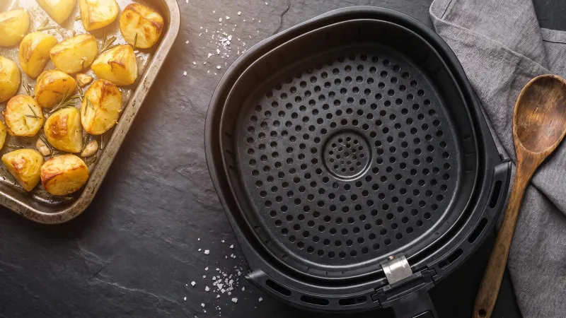 Illustrative photo of food in a black air fryer basket beside an oven dial, representing the oven-to-air-fryer converter