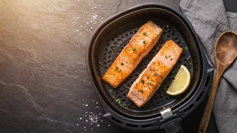 Illustrative photo of a salmon fillet in a black air fryer basket